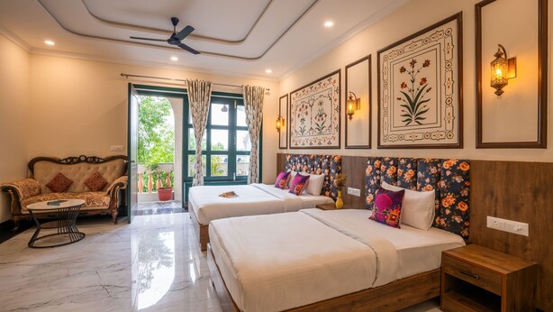 A hotel room with two beds, a sofa, a small table, and a ceiling fan. - Zostel Agra (Agra)