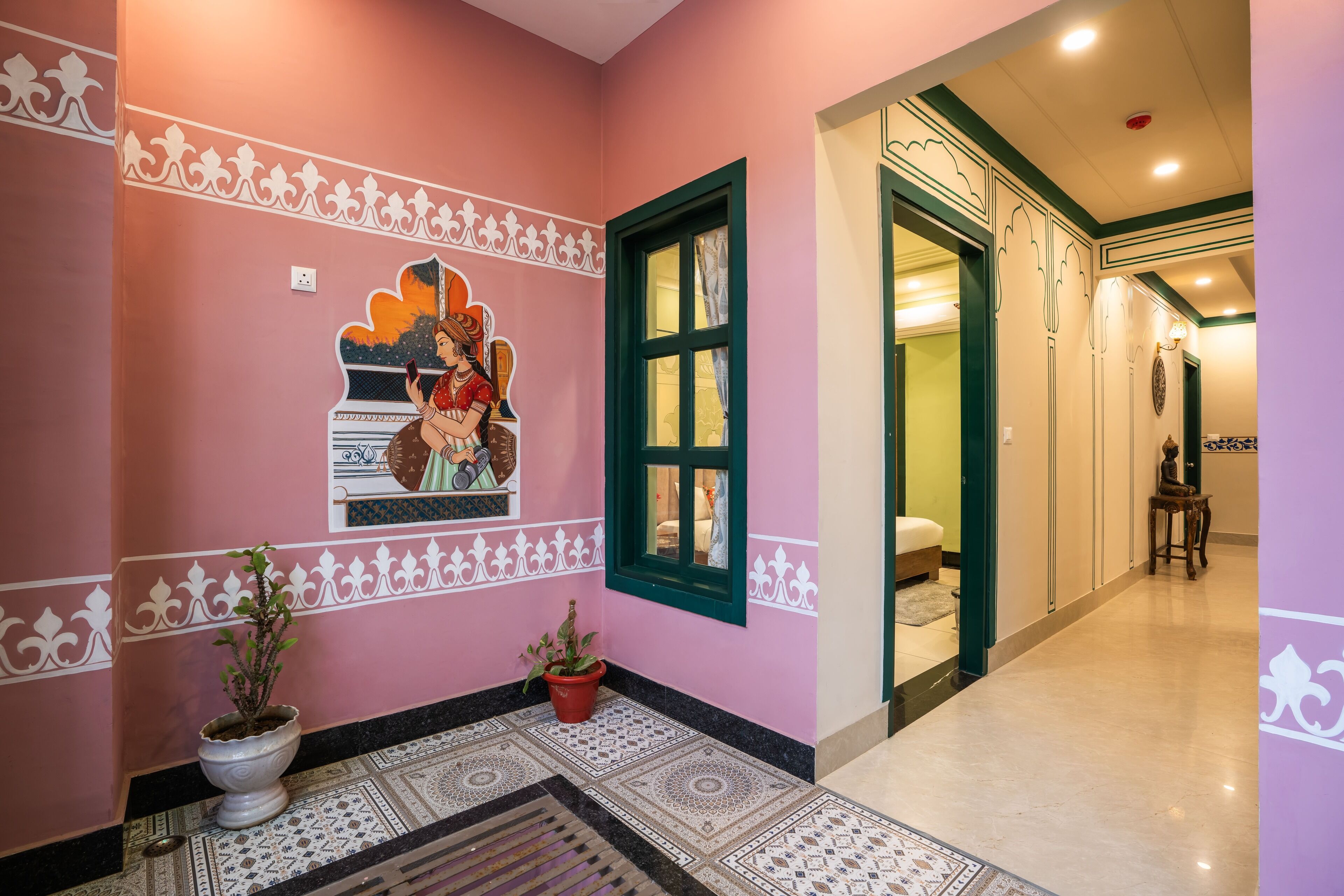 A hallway with a pink wall, decorative white patterns, a large window, and a potted plant.