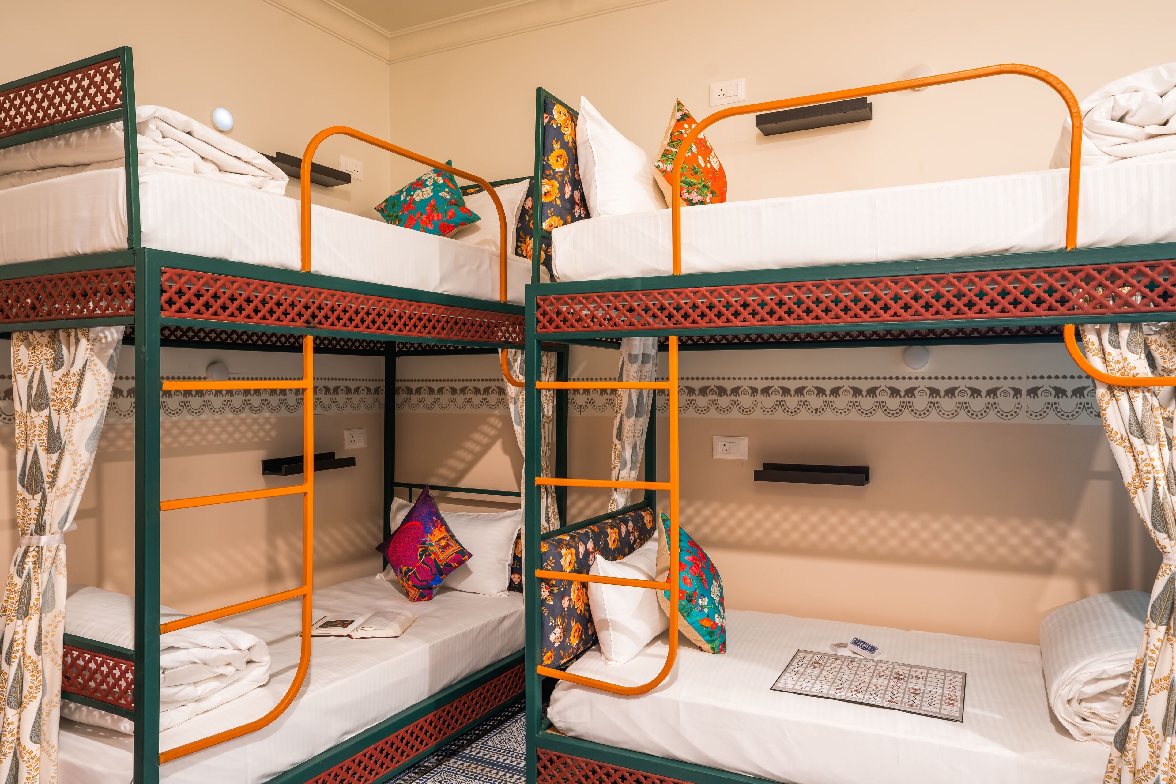 A room with three bunk beds, each with a mattress, pillows, and a blanket.