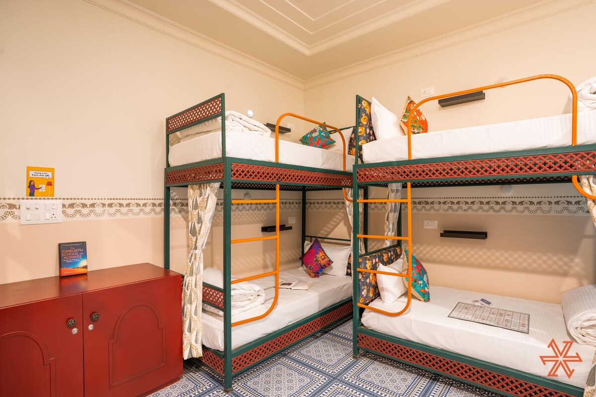 Ein Schlafsaalzimmer mit Etagenbetten, einem roten Schrank und fußbodenhohen, gemusterten Fliesen.