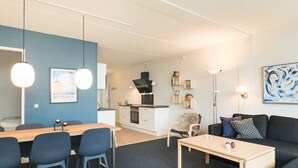 Un salon moderne comprenant un coin repas, un canapé, une table basse et une cuisine en arrière-plan.