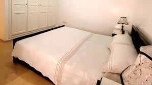 Un dormitorio con cama, mesita de noche, lámpara y armario.