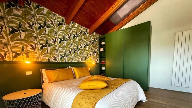 Ein Schlafzimmer mit einem Bett, einer grünen Wand, einem Holzboden und einem grünen Kleiderschrank.