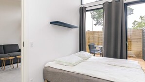 Et moderne soveværelse med en seng, et lille bord og en stol.