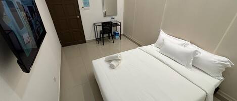 A hotel room with a bed, a desk, a chair, a TV, and a door.