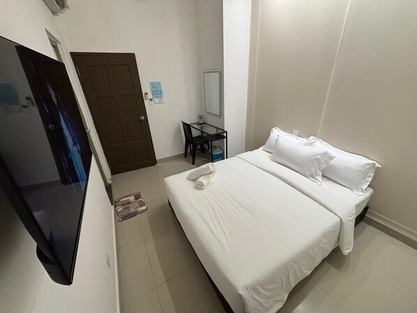 A hotel room with a bed, a desk, a chair, and a television. - One Point Hotel Airport Kuching (Kuching)