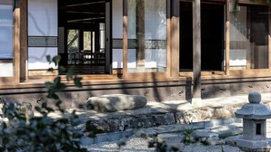 Un edificio japonés tradicional con puertas correderas, un farol de piedra y un camino de piedras.