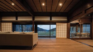 Amplia habitación con un sofá grande, zona de comedor y ventanas amplias con vistas a un paisaje nevado.