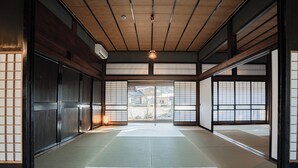 Una habitación japonesa tradicional con suelo de tatami, puertas correderas y vistas a una zona residencial.