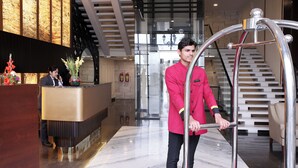 Een hotel receptie met een marmeren vloer, een receptiebalie, een trap en een modern interieur.