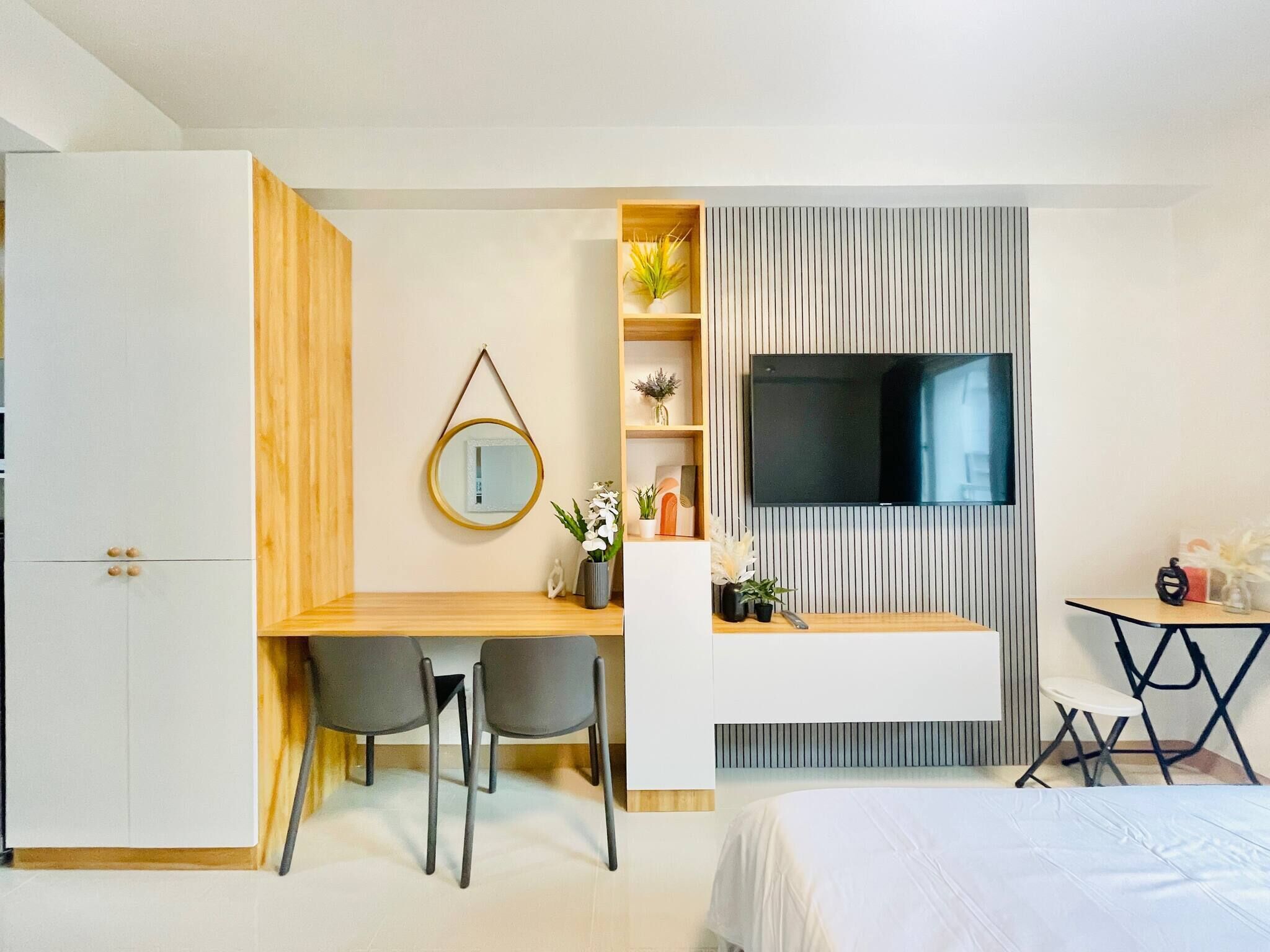 Een moderne slaapkamer met een bed, een bureau met twee stoelen, een televisie en een kleine tafel met een lamp.