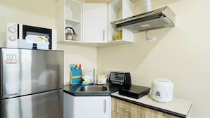 A compact kitchen with a stainless steel refrigerator, a microwave, a toaster, and a sink. - The Perfect Central Getaway (Iloilo)