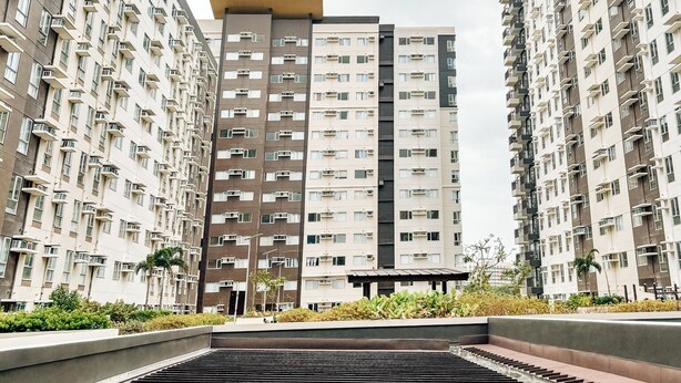A modern apartment building with multiple floors, balconies, and a central staircase leading to the entrance. - The Perfect Central Getaway (Iloilo)