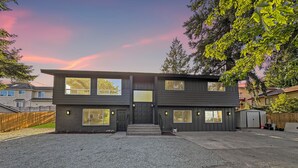 Een modern huis met twee verdiepingen, een veranda, grote ramen en een garage.