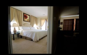 Une chambre d’hôtel avec un grand lit, deux tables de chevet, un tableau au mur et une fenêtre avec des rideaux.