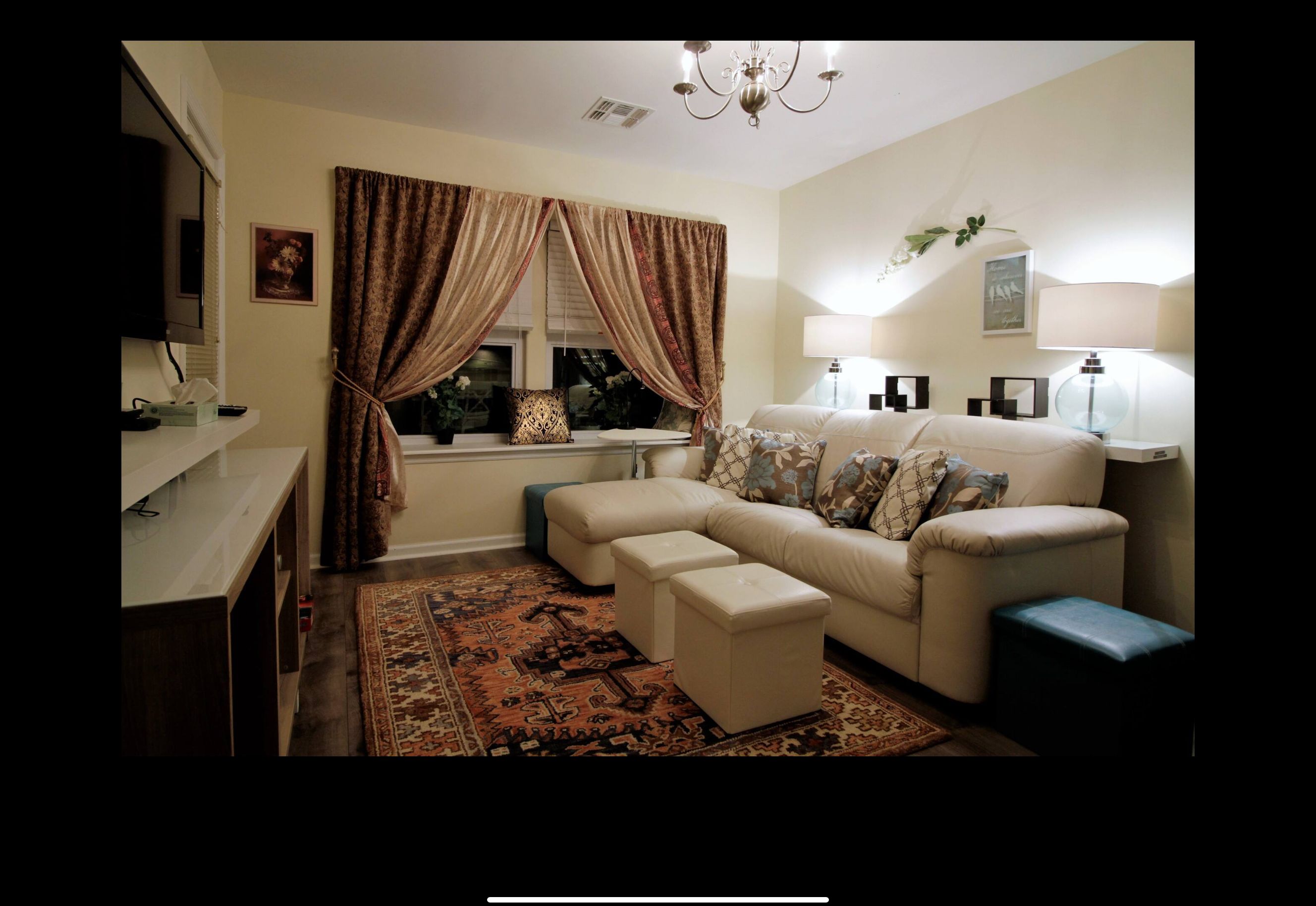 A living room with a sofa, ottoman, and a television.