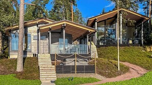 A modern building with a wooden exterior, large windows, and a covered outdoor seating area. - Villa haave by Interhome (Kustavi)