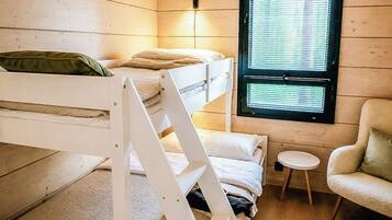 A bunk bed room with a window, a chair, and a small table.