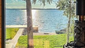 A view of a lake with a wooden deck and a stone fireplace. - Villa haave by Interhome (Kustavi)