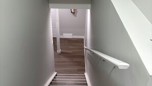 A staircase with wooden steps and white walls, leading to a room with a white door and a vent on the wall. - Cozy, clean and homely (Calgary)