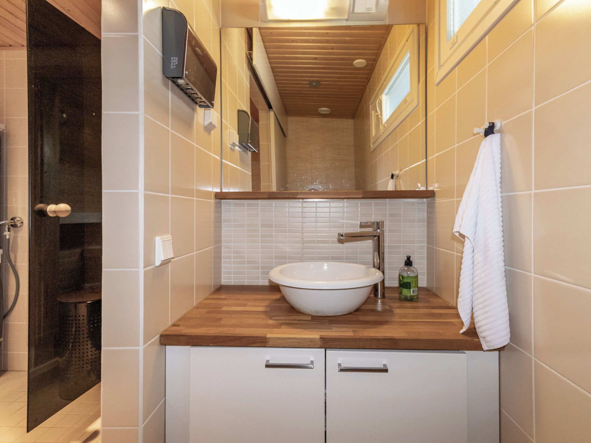 Un bagno con un mobile lavabo in legno, lavandino bianco e un asciugamano appeso al muro.