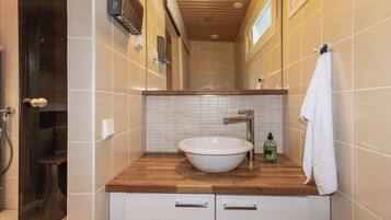 Un bagno con un mobile lavabo in legno, lavandino bianco e un asciugamano appeso al muro.