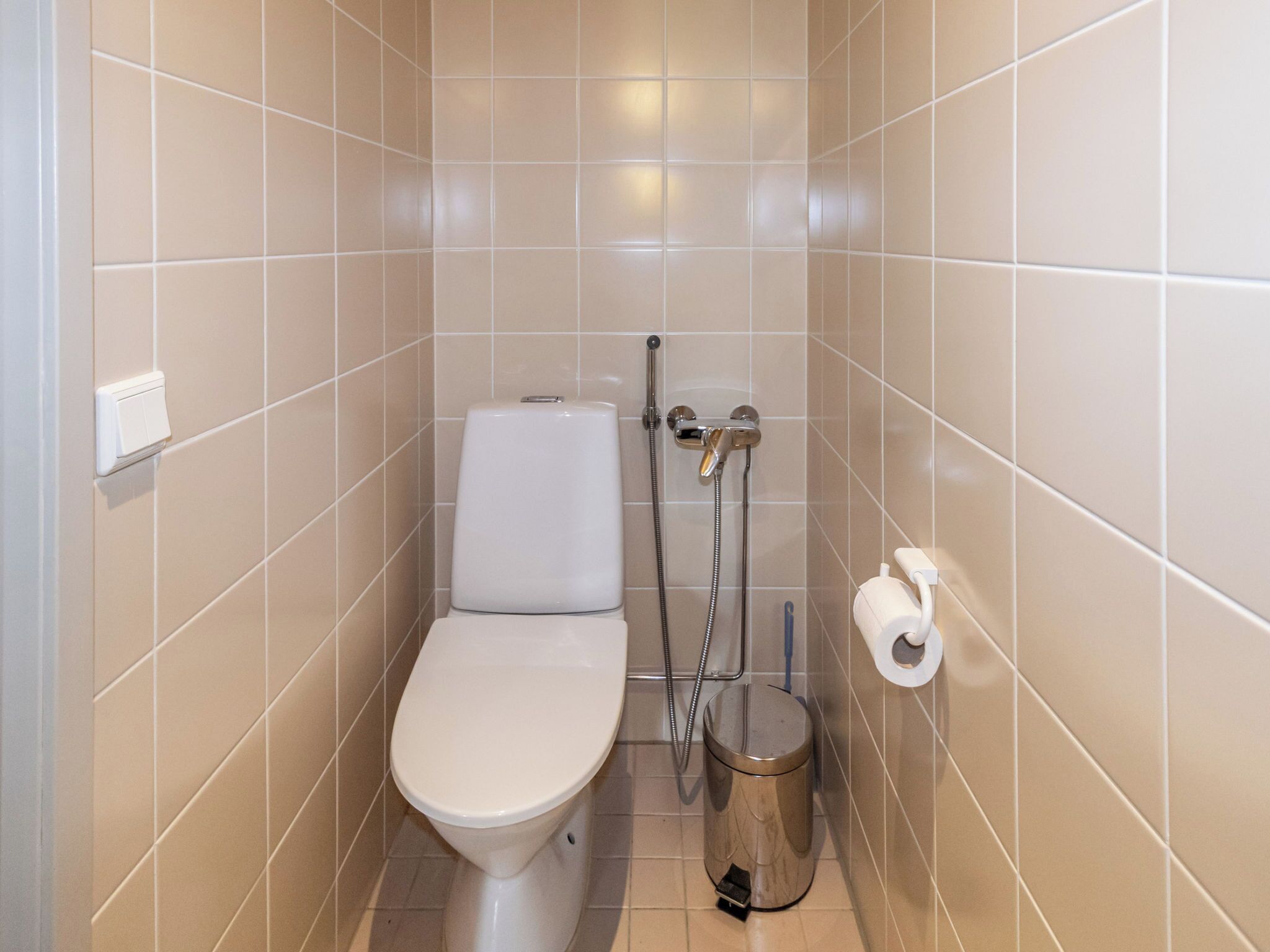 A small, modern bathroom with a toilet, a bidet, and a trash can.
