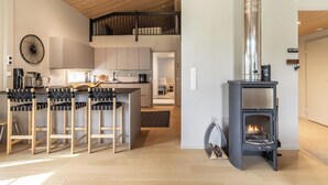 Une cuisine moderne dotée d’un îlot central, d’une cuisinière intégrée et d’un coin repas avec des tabourets de bar.