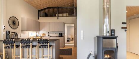Une cuisine moderne dotée d’un îlot central, d’une cuisinière intégrée et d’un coin repas avec des tabourets de bar.
