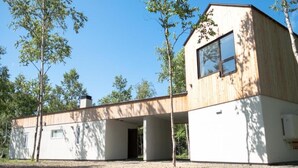 A modern building with a wooden exterior, large windows, and a covered outdoor area. - Coboushi Omoya (Niseko)