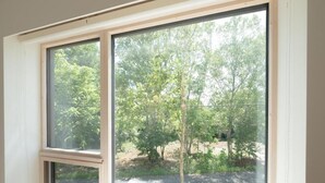 A room with a large window overlooking a wooded area. - Coboushi Omoya (Niseko)