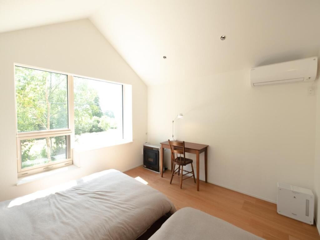 A room with two beds, a desk, a chair, and a radiator.