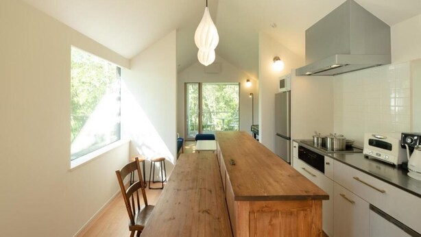 A modern kitchen with a wooden island, white cabinetry, and stainless steel appliances. - Coboushi Omoya (Niseko)