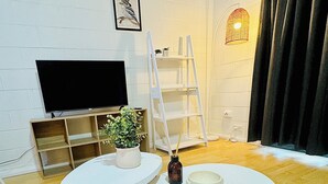 A living room with a flat-screen TV, a white shelving unit, a potted plant, and a small table with a candle. - Chic 2BR South Side Getaway Near Albury CBD (South Albury)