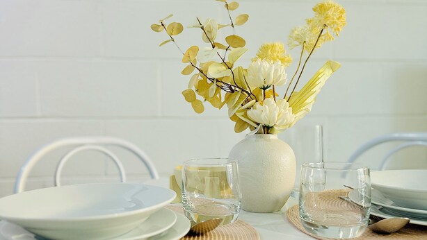 A dining table with white plates, clear glassware, and a vase with yellow and white flowers. - Chic 2BR South Side Getaway Near Albury CBD (South Albury)