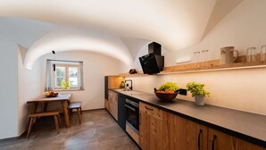 Una cocina moderna con armarios de madera, horno empotrado y comedor con mesa y banco.