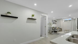 A modern kitchen with a large island, white walls, and recessed lighting. - Serene Luxury Getaway (Calgary)