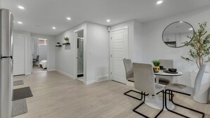 A modern dining area with a round table, grey chairs, and a potted plant. - Serene Luxury Getaway (Calgary)