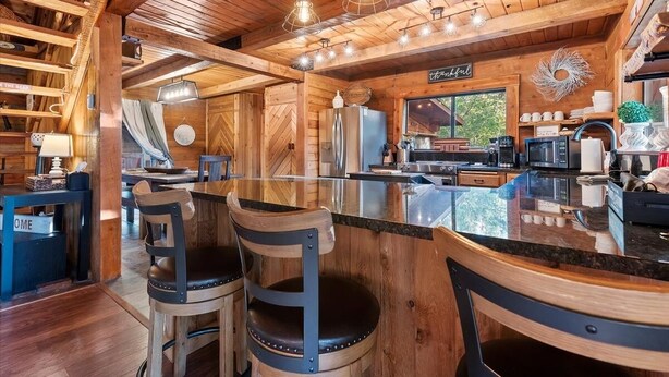 Un interior de madera con una zona de cocina, taburetes de bar y una pared con patrón de espiga.