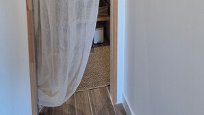 Un couloir avec une porte en bois, un rideau léger, une tapisserie murale tissée et un sol carrelé.