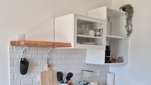 Une cuisine moderne équipée d’un four encastré, d’un évier et d’un plan de travail surmonté d’une planche en bois. On y trouve également un porte-ustensiles suspendu et une plante accrochée au mur.