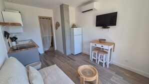 Un espace de vie compact comprenant un coin cuisine, un coin repas et un coin salon avec un téléviseur fixé au mur.