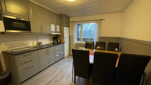 A compact kitchen with a dining area, featuring a built-in oven, microwave, and a small dining table with chairs. - 2 Person Holiday Park Home in Stenungsund (Stenungsund)