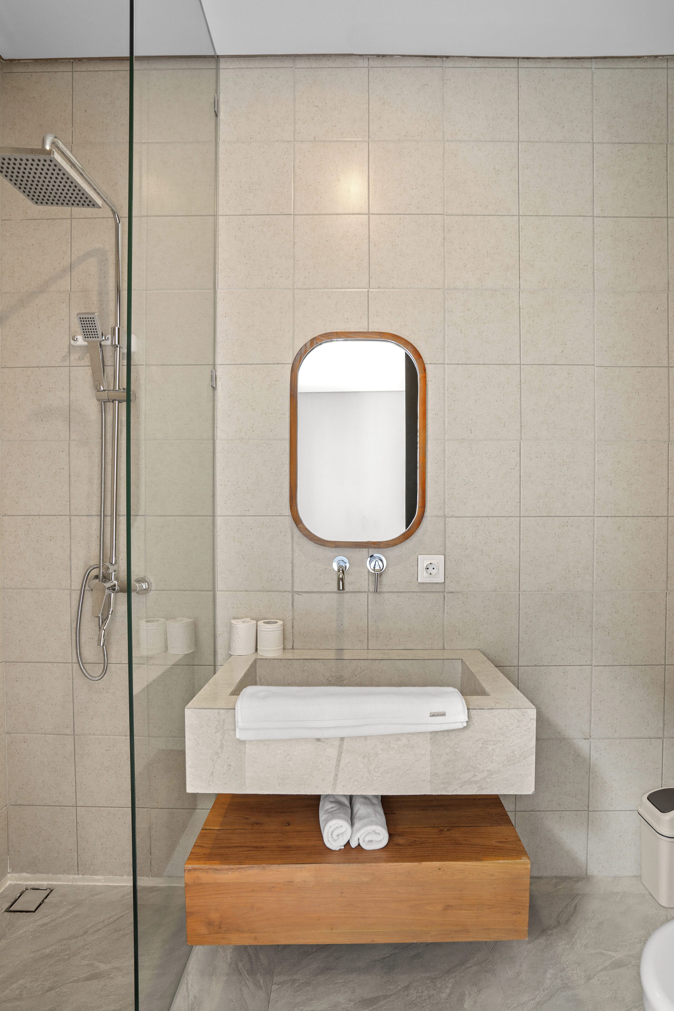 A modern bathroom with a glass-enclosed shower, a wooden vanity, and a mirror with a wooden frame.
