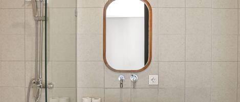 A modern bathroom with a glass-enclosed shower, a wooden vanity, and a mirror with a wooden frame.