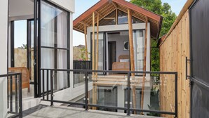 A modern house with a glass balcony, a wooden deck, and a large sliding door.