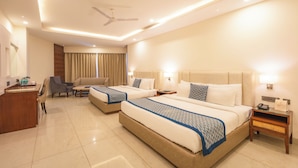 A hotel room with two beds, a desk, a chair, and a ceiling fan. - MJ AERO SUITE (Rishikesh)