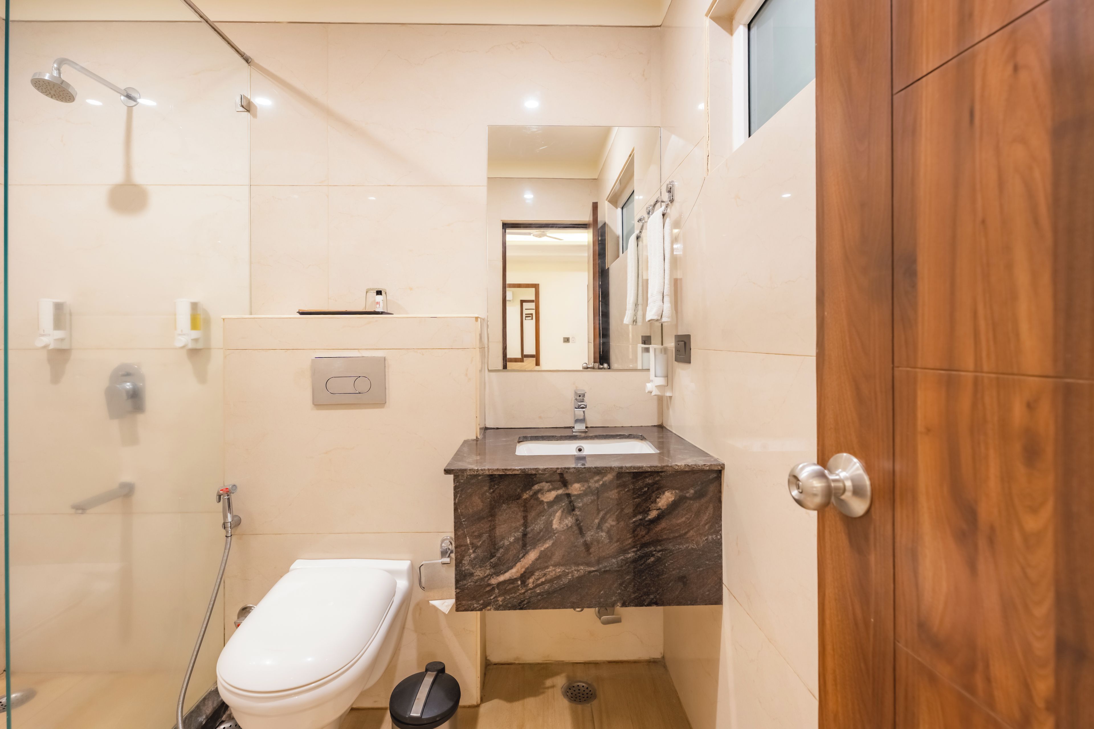 Et lille badeværelse med toilet, håndvask og brusebad.