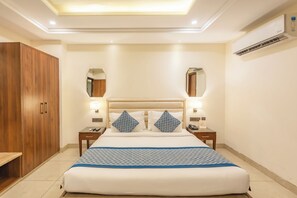 A hotel room with a large bed, wooden wardrobe, two bedside tables with lamps, and a ceiling light. - MJ AERO SUITE (Rishikesh)