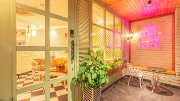 Un interior acogedor con piso a cuadros, un letrero de neón y una zona de estar con una mesa y sillas.